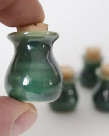 Green Miniature Pottery with Tiny Cork, held in fingers for scale
