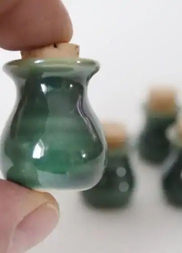 Green Miniature Pottery with Tiny Cork, held in fingers for scale