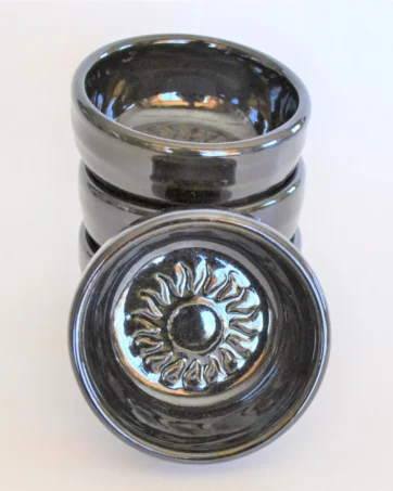 small dish with sun emblem in center, black