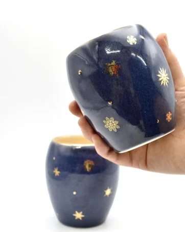 Winter Stemless Wine Glass with Gold Snowflakes, held in hand for scale